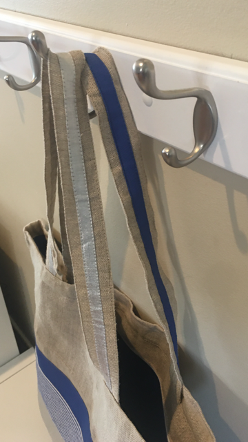 This bag has one strap with a blue strip and one strap with a sliver strip.